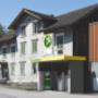 AGROLA Tankstelle in Grabs. Kleine Überdachung. Eine Tanksäule. Grosses AGROLA Logo auf Dach. Dahinter ein Wohhaus