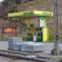 AGROLA Tankstelle in Mogelsberg; Im Vordergrund Zuggleise und Paletten mit Setzsteinen. AGROLA Tankstelle mit zwei Säulen und Zahlterminal. Totem mit Preisen im Hintergrund