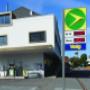 AGROLA Tankstelle in Kirchlindach; eine Tanksäule links bei Hauswand; im Vordergrund Totem mit AGROLA Logo, Preisen und Volg-Schild