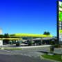 AGROLA Tankstelle in Lohn-Ammannsegg - Bätterkinden; Rechts Totem mit Landi Laden Logo, AGROLA Logo, digitaler Preisanzeige, selfwash; azurblauer Himmel; geschwungenes Dach mit drei Säulen