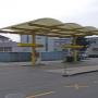 AGROLA Tankstelle in St. Margrethen, Sankt Margrethen; geschwungene Überdachung mit gelbem Gerüst. Im Hintergrund Gebäude mit grauer Fassade.