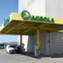 AGROLA Tankstelle in St. Margrethen, Sankt Margrethen; geschwungene Überdachung mit gelbem Gerüst. Im Hintergrund Gebäude mit grauer Fassade.