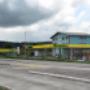 AGROLA Tankstelle in Buttisholz mit TopShop und Landi; im Vordergrund Strasse mit Fussgängerstreifen, links Totem mit Landi Schild, AGROLA Schild, digitaler Preisanzeige Treibstoff, selfwash dach