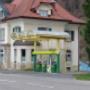 AGROLA Tankstelle in Brunnadern an Dorfstrasse gelegen. Rechts Totem mit AGROLA Logo und darunter digitaler Preisanzeige. Geschwungene Glasüberdachung der Tankstelle mit drei Tanksäulen
