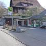 AGROLA Tankstelle in Maschwanden; zwei Tanksäulen zwischen Gebäuden gelegen. Links Pfeiler mit AGROLA Logo und Preisschildern