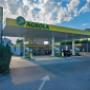 AGROLA Tankstelle in Arbon mit LAVEBA Shop. Im Vordergrund Einfahrt mit Pfeil. Links Totem mit AGROLA Logo, digitaler Preisanzeige und rotem Shop Logo
