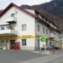 AGROLA Tankstelle in Weesen bei FLY Garage. Eine Tanksäule direkt unter Balkon gelegen. Daneben Zahlterminal und Selecta Automat. Im Vordergrund Strasse mit Einfahrt.