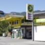 AGROLA Tankstelle in Altstätten, St. Gallen, Überdachung, gelbes Gerüst. Zwei Tanksäulen mit einem Zahlterminal. Im Hintergrund Wohnhaus.