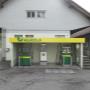 AGROLA Tankstelle in Menzingen. Zwei Tanksäulen mit Zahlterminal unter kleinem Vorstand. Im Hintergrund Gebäude mit grauer Fassade.