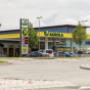 AGROLA Tankstelle in Volketswil; im Vordergrund Kreisel. Mittig im Bild AGROLA Logo entlang Dach. Links Totem mit Landi Logo, AGROLA Logo und digitaler Preisanzeige. Mit TopShop.