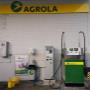 AGROLA Tankstelle in Ennetbürgen. Eine Tanksäule mit Tankautomat. Mülleimer und gelber Putzeimer und Giesskanne daneben. Über der Tanksäule AGROLA Banner mit Diskus.