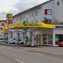 AGROLA Tankstelle in Elgg bei Renault Garage; geschwungenes Dach; Tankstelle mit zwei Tanksäulen; an Dach digitale Preisanzeige mit AGROLA Logo, Strasse im Vordergrund
