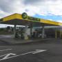 AGROLA Tankstelle in Tafers mit TopShop; links Einfahrtmarkierung mit Pfeil; Tankstelle überdacht mit mehreren Tanksäulen und Pfeilern; Himmel bewölkt