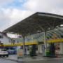 AGROLA Tankstelle und LAVEBA Shop in St. Galen an der Zürcherstrasse, überdacht, zwei Tanksäulen im Vordergrund, links weisses Auto geparkt, im Hintergrund Shop mit blauem Sonnenschirm und Truhe davor
