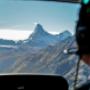 This photo captures a unique moment from one of our FunFlights helicopter tours to the iconic Matterhorn. Taken from the back seat, the image shows part of the cockpit and our pilot in action, with the world-famous peak in the distance. Starting from the