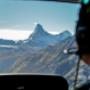 This photo captures a unique moment from one of our FunFlights helicopter tours to the iconic Matterhorn. Taken from the back seat, the image shows part of the cockpit and our pilot in action, with the world-famous peak in the distance. Starting from the