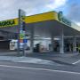 AGROLA Tankstelle in Zell, Luzern, Einfahrt im Vordergrund mit Pfeilmarkierung, links Totem mit AGROLA Diskus Logo, digitaler Preisanzeige, AdBlue, TopShop Logo darunter; im Hintergrund TopShop