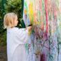 Child spray painting outdoors at ELABasel international preschool and Kita in Basel