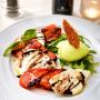 Unsere sommerliche Caprese, aromatische Tomaten und cremiger Mozzarella treffen auf frischen Rucola, Basilikum und ein erfrischendes Basilikumsorbet. Ein leichter Klassiker, überraschend neu interpretiert.
